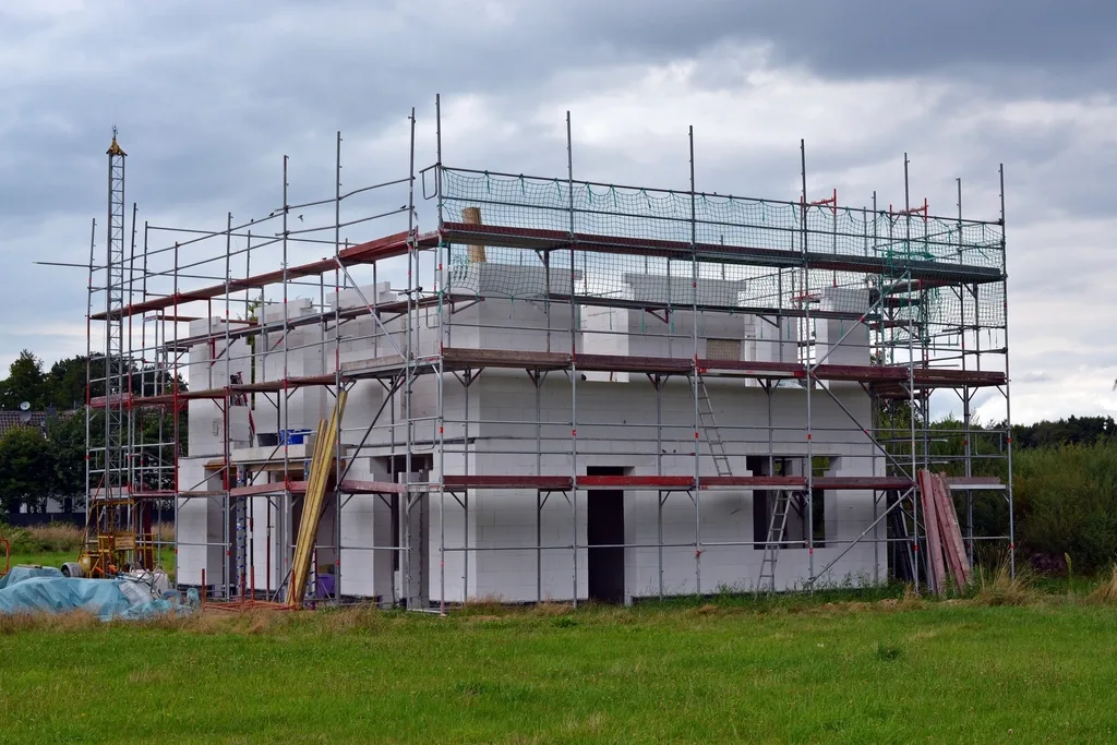 Een bouwplaats met steigers langs een casco in aanbouw.